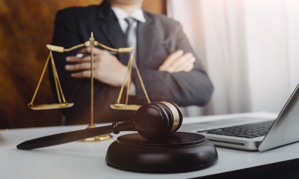 Business and lawyers discussing contract papers with brass scale on desk in office. Law, legal services, advice, justice and law concept picture with film grain effect