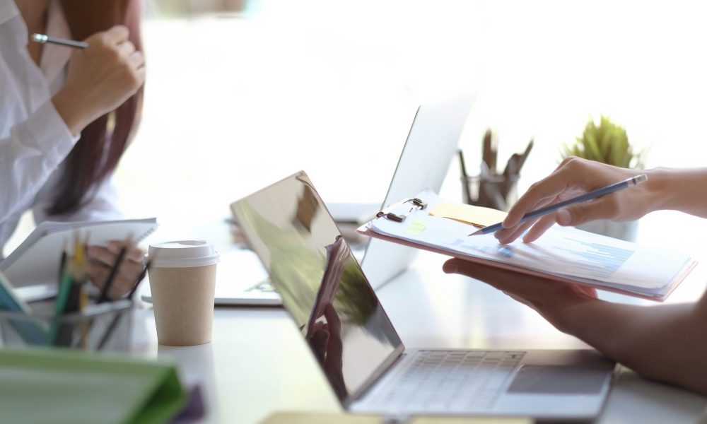 Team Businessman holding pencil working on financial report  and business woman holding pens and holding paper in office.